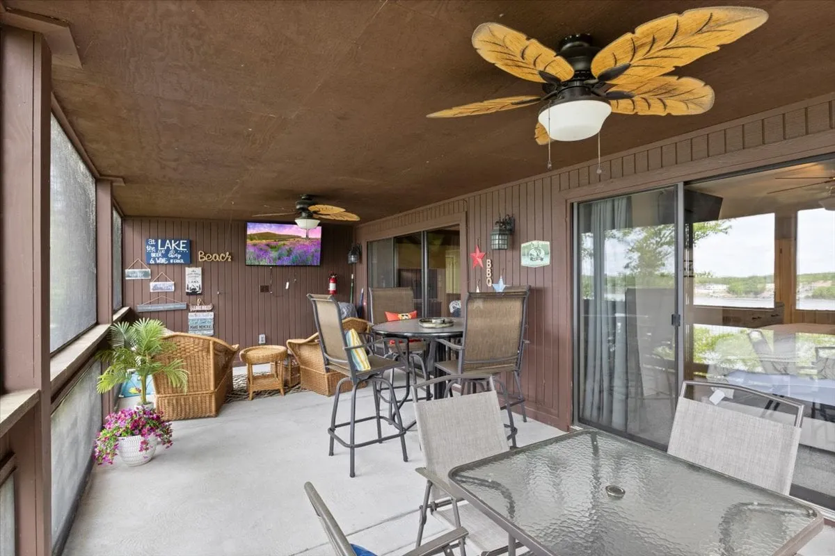 A spacious outdoor dining area featuring ceiling fans with leaf designs, comfortable seating, a large dining table, and decorative wall art. The setup encourages alfresco meals and socializing as the sun sets.