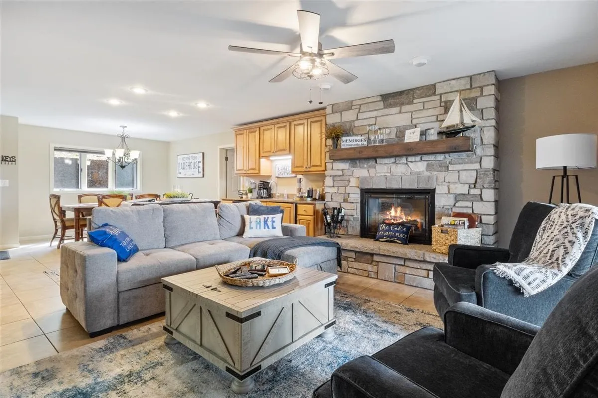 A cozy family room scene featuring a fireplace, coffee table, sofa, kitchen, and dining area all within an open-concept layout. This inviting space is suited for family gatherings, playing games, and sharing laughter after a day exploring outdoors.