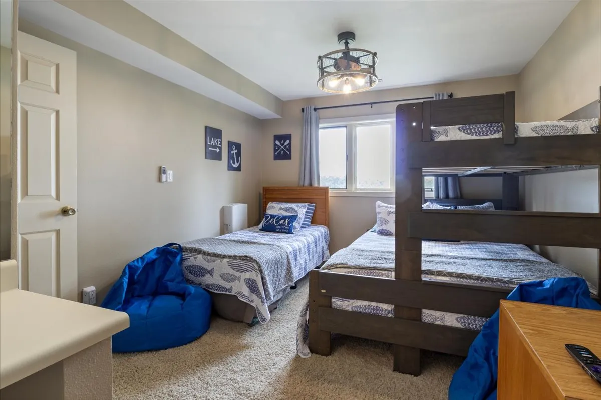 A playful and vibrant bunk room outfitted with a bunk bed, bean bag chair, decorative pillows, and cheerful wall art. The setup is inviting for children, with ample floor space for play and relaxation, evoking a fun and safe hideaway for younger guests.